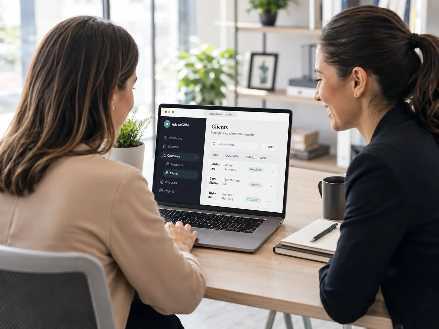 Two consultants reviewing AdviseCRM client relationships on a laptop